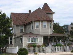 a large gray house with a white picket fence