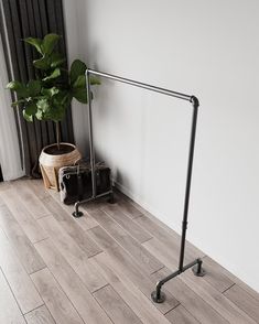 a black suitcase sitting on top of a wooden floor next to a metal rail and potted plant