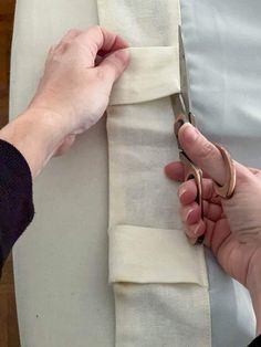 someone is cutting fabric with scissors on a piece of white material that has been folded over