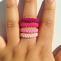 a woman's hand with three different colored rings on her fingers and one is holding the other