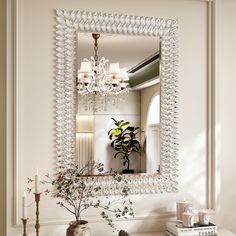 a mirror that is on the wall above a table with a vase and some flowers