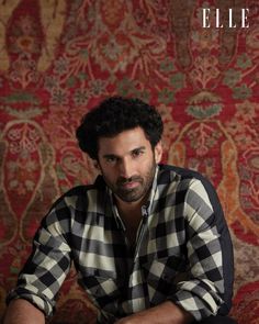 a man sitting on top of a wooden table next to a red and gold wall