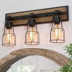 three light fixtures mounted on the wall above a mirror and potted plant in front of it