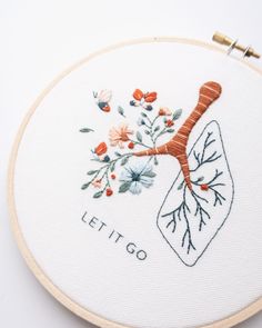 an embroidery project with the words let it go written in white and orange flowers on top