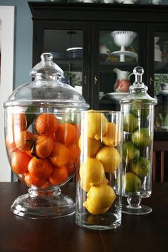 two glass containers filled with fruit sitting on top of a table