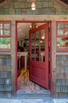 a red door is open on the inside of a small cabin with wood flooring