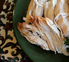 a green plate topped with sliced up turkey and parsley on top of a table