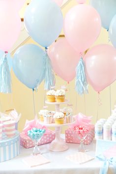 a table topped with cupcakes and balloons