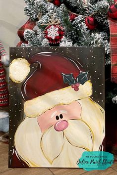 a painting of a santa clause on a canvas next to a christmas tree