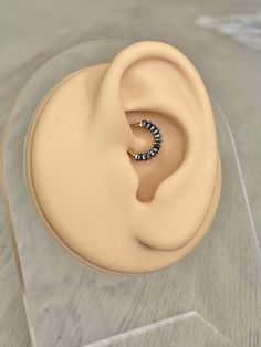 a pair of ear rings sitting on top of a clear display case in front of a white background