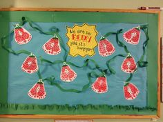 a bulletin board decorated with paper strawberries and green ribbon tied around the edges that says, we are so berry