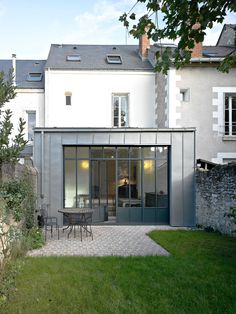 an outdoor dining area in front of a large white building with glass doors and windows