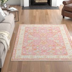 a living room filled with furniture and a rug on top of a hard wood floor