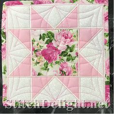 a pink and white quilt with flowers on the front is sitting on a marble surface