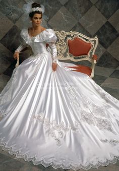 a woman in a white wedding dress sitting on a chair with her hand on her hip