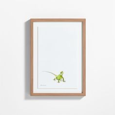 a framed photograph of a green lizard on a white wall with a wooden frame in front of it