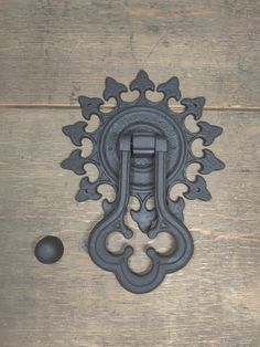 an ornate iron door handle on a wooden surface with a black ball in the foreground