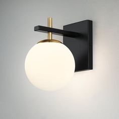 a black and gold wall light with a white ball on the back of it's arm