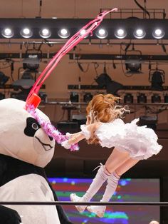 a woman in white dress standing next to a giant stuffed animal