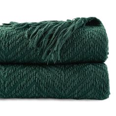 two dark green towels folded on top of each other, one with fringed ends