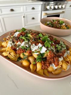 pasta with meat sauce and parsley on a plate next to a bowl of salad