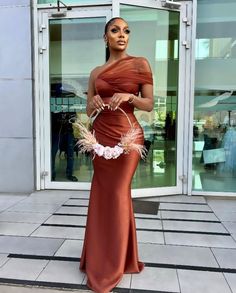 a woman in an orange dress standing outside