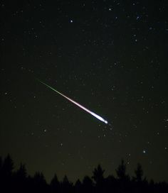 an object is seen in the night sky with stars above it and trees around it