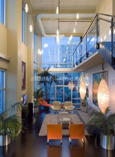 a living room filled with lots of furniture and tall windows next to a stair case