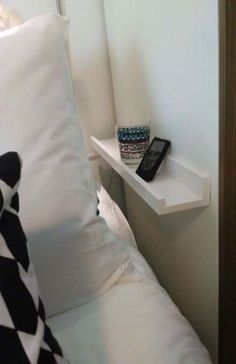 a cell phone sitting on top of a white pillow next to a shelf with a black and white checkered pillow