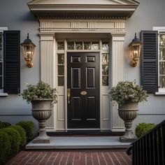 a black door with two planters in front of it and some lights on the side