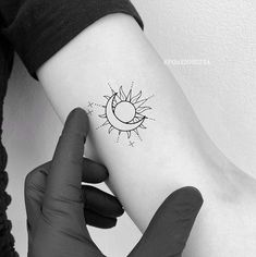 a person with a tattoo on their arm holding up the sun and moon in front of them