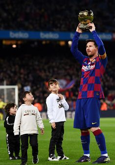 a man holding up a trophy while standing next to two small children on a soccer field