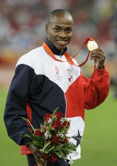 a man holding a medal and flowers in his hand