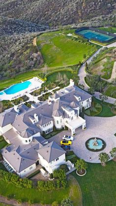 an aerial view of a large white mansion with a pool in the middle and lots of greenery surrounding it