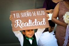 a young boy holding up a sign that says realdad in spanish and white writing