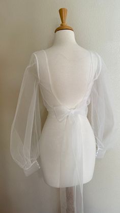 a mannequin wearing a white dress with sheer sleeves