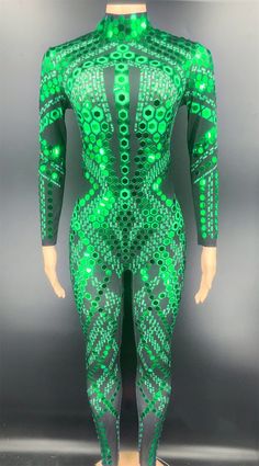 a mannequin with green and black designs on it's body, standing in front of a gray background