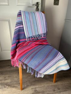 a colorful blanket sitting on top of a wooden chair in front of a white door