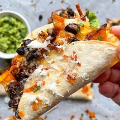 a hand holding a tortilla filled with black beans and cheese