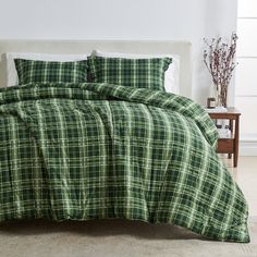 a bed with green plaid comforter and pillows