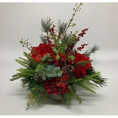 a vase filled with red flowers and greenery