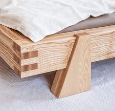 a wooden bed frame sitting on top of a white carpeted floor next to a pillow