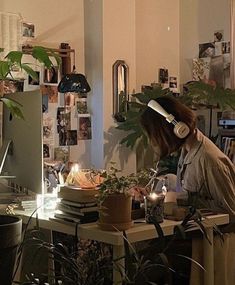 a woman sitting at a desk with headphones on and plants in front of her