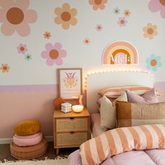 a bedroom decorated in pastel colors with flowers on the wall and pink bedding