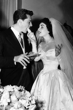 a man and woman standing next to each other in front of a cake