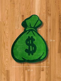 a green bag with a dollar sign on it sitting on the floor next to a ruler