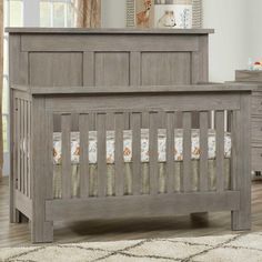 a baby crib in a room with a rug on the floor and pictures above it