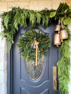 a blue front door decorated with greenery and bells