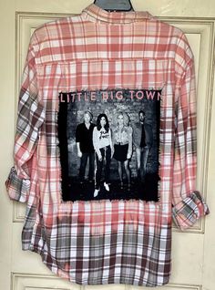 This is ONE OF A KIND Little Big Town flannel shirt. Upcycled/Bleached/Distressed Long sleeve Size Men's XL 100% Cotton This particular flannel has two pockets on the front side of the shirt and is a long sleeve button up. An original Little Big Town concert tee has been sewn into the back of the flannel. The flannel is frayed around the tee, trimming it out, giving it distressed/vintage style look. And the flannel has been bleach.  All my shirts are A ONE OF A KIND. They are all upcycled and previously owned so there will be signs of wear and tear. But this is what make each one unique in its own way and for sure makes them the most comfortable.  *NOTE: If your going to wear this as a oversized jacket it's recommended that you buy a size bigger than you would normally wear. Here are some Band Clothes, Distressed Long Sleeve, Little Big Town, Big Town, Band Outfits, Concert Tees, Vintage Plaid, Oversized Jacket, Concert Outfit