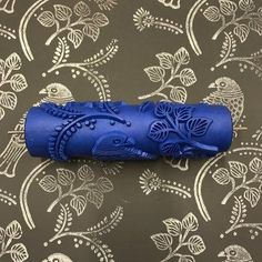 a blue object sitting on top of a table next to a wallpaper covered with birds